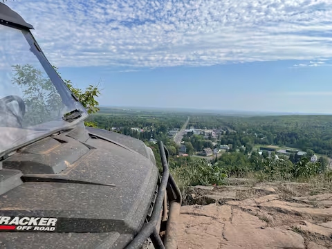 ORV on a rocky overlook above a small town and forested hills