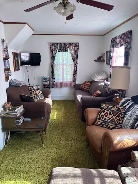 Bright Yooper Lodge living room with sofas, chairs, TV, and daylight through windows