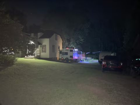 Yooper Lodge exterior at night with vehicles, camper, and lights on the lawn